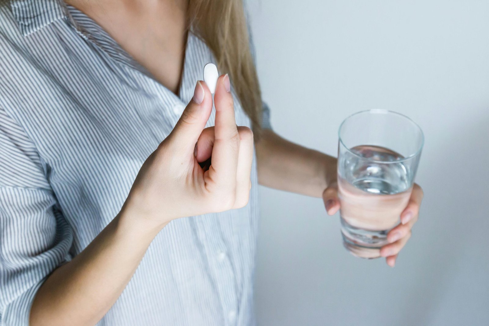 Wanita Memegang Gelas dan Suplemen Nutrisi
